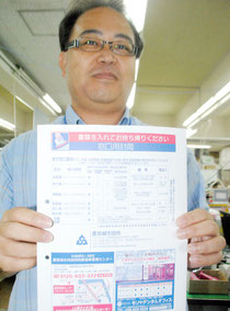 豊見城市役所で市民に提供されている封筒を持つ石垣市職員(17日午後)