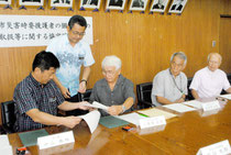 各地域の公民館長たちが見守る中、協定書を交わす中山市長と入嵩西会長=30日午後、市役所