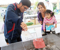 家族で石垣牛のバーベキューを楽しむ大会来場者=24日午後、市中央公園陸上競技場入口