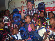El periodista Balbueno Medina, presidente de FUNCOMYSA, momentos en que hace distribucion de los útiles escolares entre niños de Santo Domingo Norte