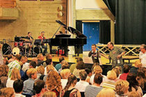 Dozent Hubert Minkenberg (2. v. re.) führt die zahlreichen Sänger und Sängerinnen in der Aula zu einem großen Chor zusammen. Den intensiven Proben in der Aula folgte ein Abschlusskonzert. Foto: Uwe Heldens