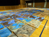 小学校の全児童分の土の絵を描いて体育館に敷きつめ、１年生から６年生まで、みんなで土の飛び出す絵本になったり、土の絵の中を潜り抜ける遊びをしたり、土の絵を身体にまとってファッションショーをしたり、おかげさまで楽しい土の時間、愛の時間に包まれたワークショップになりました♪