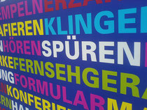 Plakat mit Aufschrift: Spüren, Fernsehen, Klingen