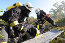 Außerhalb der Lagerhalle finden Normen Ziegert und Felix Berthold den ersten Verletzten. Die Feuerwehrmänner bringen ihn in Sicherheit. (FOTO: SUSANNE THON)