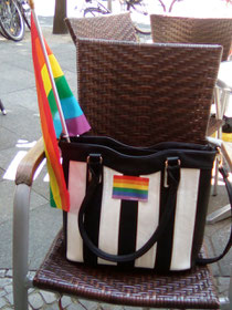 Meine Lieblingshandtasche mit Regenbogenaufkleber und -fahne im Juli 2016 vorm Café Berio.