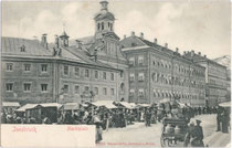 Marktbetrieb vor dem ehemaligen Ursulinenkloster (im Baukern die Hechtburg), Innrain Nr. 5 und -kirche (heute Ursulinensäle), Innrain Nr. 7. Lichtdruck 9 x 14 cm; Impressum: Verlag Robert Warger, Innsbruck.  Inv.-Nr. vu914ld00033