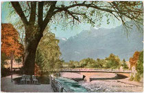 Meraner Kurpromenade zwischen Reichsbrücke (heute Postbrücke, rechts im Bild) von 1909 und der Theaterbrücke. Photochromdruck 9 x 14 cm; ohne Impressum um 1910.  Inv.-Nr. vu914fat00081