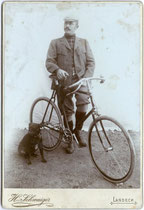 Junger Mann mit Rennsportrad in Norfolk-Jacket und Knickerbockers.  Gelatinesilberabzug auf Untersatzkarton  16,6 x 10,8 cm. Impressum:  H(einrich). Schwaiger, Landeck in Tirol  (vormals in Sterzing) um 1900. Inv.-Nr. vuCAB-00050