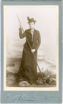 Dame in Alpinkleidung und mit Bergstock im Atelier. Albuminabzug auf silbergeprägtem Untersatzkarton 10,5 x 6,5 cm (Visitformat). Impressum: Jos(ef). Stiegler, Stumm im Zillerthal um 1895.  Inv.-Nr. vuVIS-00072