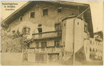 Rückseite vom Rammingerhaus, ehemaliger Gasthof „Schwarzer Adler“, Achenseestraße 34 in Jenbach, Bezirk Schwaz, Tirol. Lichtdruck 9 x 14 cm; Impressum: Verlag Georg Ramminger, Jenbach; postalisch befördert 1916.  Inv.-Nr. vu914ld00223