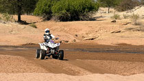 QUAD TRAVERSANT UN COURS D'EAU ASSÉCHÉ AU CŒUR DU DAMARALAND, EN NAMIBIE, LORS D'UNE AVENTURE OFFROAD.