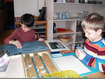 Die Schulanfänger Paul und Marcus stempeln Buchstaben und Wörter.