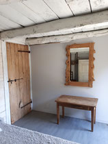 chambre dans une ambiance vintage avec poutres apparentes et table porte-valise et miroir