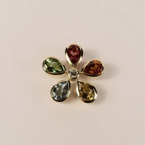 N°224 ANHÄNGER BLUME - Aus 750/- Gelbgold poliert. Um einen 0,09 Carat Brillant sind zu einer Blume angeordnet, ein roter & grüner Turmalin, ein Mandaringranat, ein Aquamarin und ein Goldberyll. 