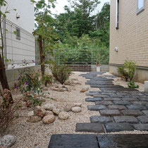 中庭は雑木類を植え、石畳と枕木調の敷石で庭の奥へつづく道、そして突き当りにはレンガを積み上げた花壇があります。