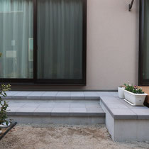 デッキと玄関をつなぐコンクリート平板のテラス階段。掃き出し窓に腰かけてつかうにも最適です。