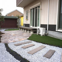 完成したお庭、ポルフィードの石張りテラスと既存デッキを中心に、枕木ステップと人工芝を敷きこみます。