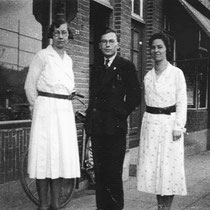 Jos Leunissen met Dien (l) en Mien Diederen (r) onder aan de stationsstraat voor in 1936 gesloopte panden: vlnr.: Habets: de Ster, de voordeuren van bovenwoningen Diederen en Brummans, Textielzaak Gezusters Gerards, Kruidenierswinkel Brassé