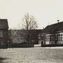 De Sint Bavoschool met paarden , in de tijd dat er nog gras groeide op het Markt/kermisplein waar periodiek paardenmarkten werden gehouden. Aan de linkerkant hebben nog lang de palen met stangen gestaan waar de paarden aan werden vastgelegd