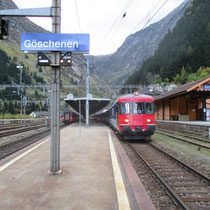 Interregio Göschenen-Zürich am 05.10.2014 in Göschenen, rechts der alte Güterschuppen mit dem älteren Bahnhofsschild.