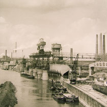 Blick von der Eisenbahnbrücke auf den Nordhafen der Niederrheinischen Hütte in Duisburg-Hochfeld. Im Hintergrund Brücke der Solidarität, Baubeginn 1945, Eröffnung 1950.