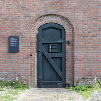 Buitenmuur van binnenaf gezien met de poort die gebruikt werd om de ter dood veroordeelde gevangenen weg te voeren naar de Waalsdorpervlakte waar men gefusilleerd werd