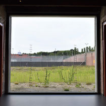 Een van de ramen met zicht op de locatie van voormalige cellenblokken inclusief nummers van de gevangenen