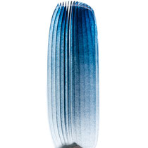 Grande sculpture en verre bleu de Prusse, translucide aux lignes verticales, installée sur une base minérale.