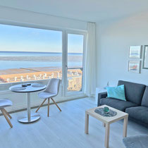 Heller Wohnbereich der Ferienwohnung Nautilus Nr. 27 mit weitem Blick auf Strand und Meer