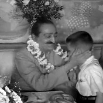 1956 ; Young Larry Karrasch garlanding Meher Baba at Longchamps Restaurant, New York.