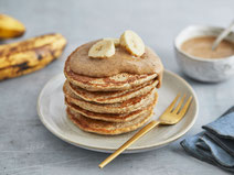 Vegane Bananen-Haferflocken-Pancakes serviert auf einem Dessertteller mit goldener Dessertgabel.