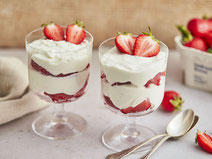 Erdbeer-Quark serviert in zwei Gläsern, garniert mit ein paar Scheiben frischer Erdbeeren.