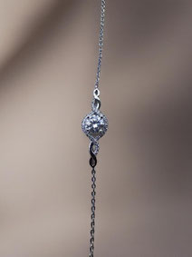Close-up of a delicate silver bracelet with a round clear stone and fine detailing against a soft neutral background. Minimalist and elegant product photo.
