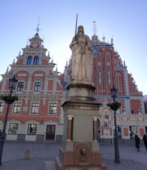 View of Roland statue, House of Blackheads and St. Peter's Church steeple in Old Riga with tourists in foreground