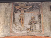 Medieval moulding in Riga's Old Town of a knight in armour kneeling before Christ on the cross.