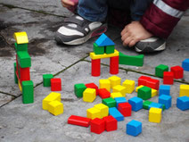 Kind spielt mit bunten, unterschiedlich förmigen Holzklötzen