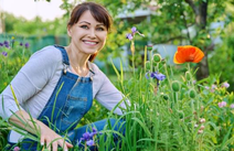Eine lächelnde Frau sitzt vor einer blühenden Blumenwiese.