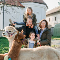 Glückliche Familie mit Kindern und Alpakas auf dem Pointnerhof.