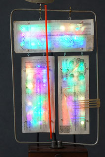 Assemblage light art sculpture made from a radio antenna, 19th century French checks, plexiglas rod, hair combs,  and colored LEDs. Light from the LEDs is refracted through plexiglas pieces, before it is projected from behind to the front of the 3 checks.