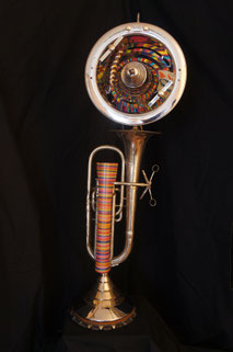 Assemblage light art sculpture made from a silver baritone horn, a chrome reflector dish, and a collection of painted watch springs which "shimmy" as they revolve around an axis. 