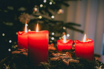 Vier brennende rote Kerzen auf einem Adventskranz.