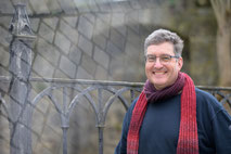 Portraitfoto eines Mannes vor einer Mauer und schmiedeeisernem Zaun fotografiert von Angelika Zwick