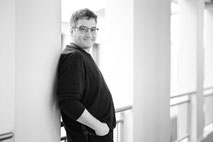 Portraitfoto eines Mannes, der sich an einen Betonpfeiler anlehnt fotografiert von Angelika Zwick