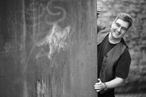 Portraitfoto eines Mannes, der hinter einer Mauer hervorguckt fotografiert von Angelika Zwick