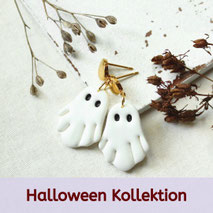 Goldene Ohrstecker mit weißen Geister-Anhängern, Halloween-Schmuck auf Stoff mit Trockenblumen dekoriert.