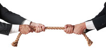 Zwei Männer ziehen entgegengesetzt an einem Seil.