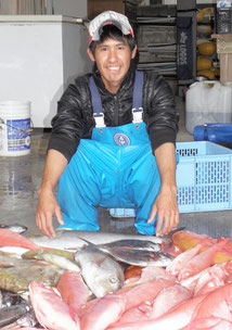 波照間沖で一泊操業。水揚げした魚の前で「まあまあの釣果」と話す将世さん=12日午前、自宅で