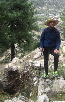 Un homme avec un chapeau coloré et des baskets, la montagne en fond