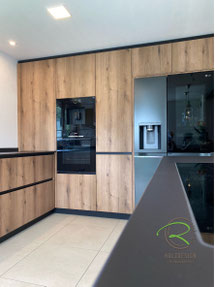 Wohnküche in Tuttlingen in schwarz und Eichen-Holzdekor mit deckenhoher Hochschrankzeile mit schwarzem Side by Side Kühlschrank, schwarzer Keramik Arbeitsplatte und flächenbündigem Induktion Muldenlüfter