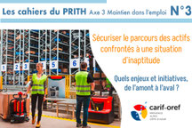 Une femme et un homme en tenue de manutentionnaire dans une usine tirant un transpalette